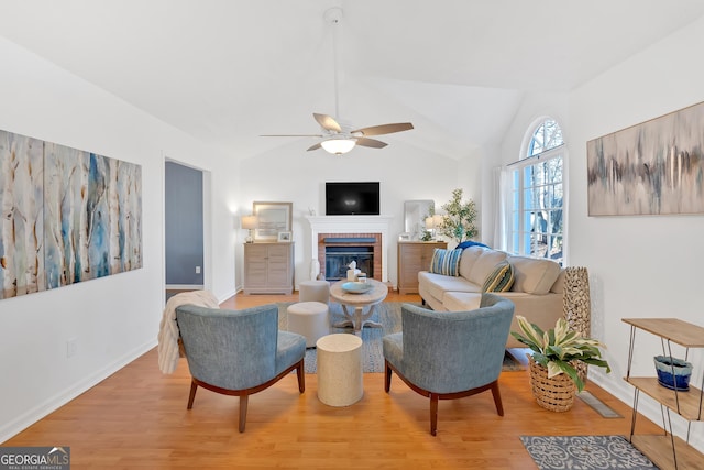 living room with lofted ceiling, a brick fireplace, light hardwood / wood-style flooring, and ceiling fan