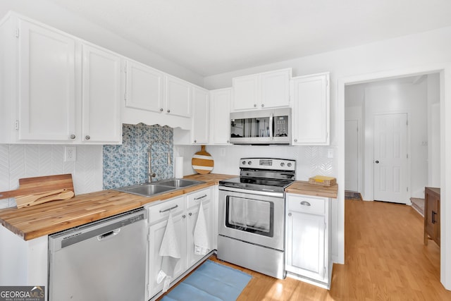 kitchen featuring butcher block countertops, white cabinetry, sink, stainless steel appliances, and light wood-type flooring