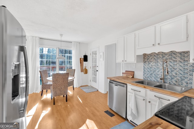 kitchen featuring appliances with stainless steel finishes, sink, wooden counters, and white cabinets