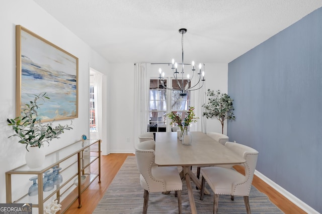 dining room with an inviting chandelier, a textured ceiling, and light wood-type flooring