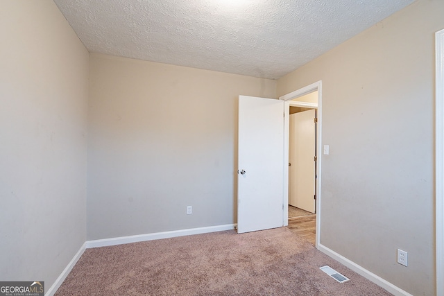 empty room with light carpet and a textured ceiling