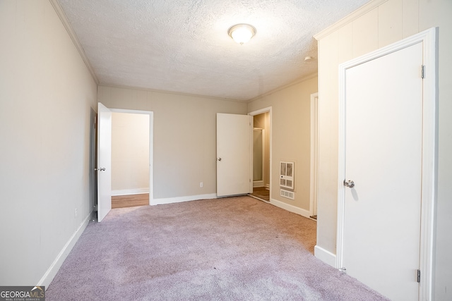 unfurnished bedroom with heating unit, light carpet, and a textured ceiling