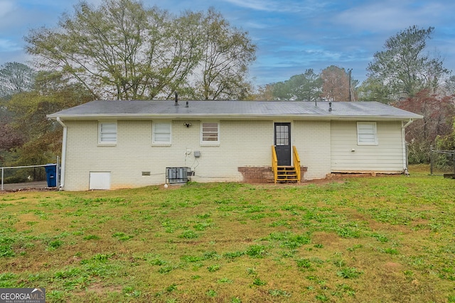 back of property featuring a lawn and central AC