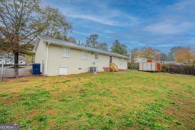 rear view of property with a yard, cooling unit, and a storage unit