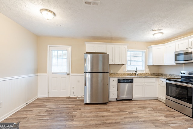 kitchen with light hardwood / wood-style flooring, white cabinets, stainless steel appliances, and sink