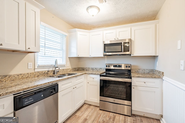 kitchen featuring a textured ceiling, sink, white cabinetry, and stainless steel appliances