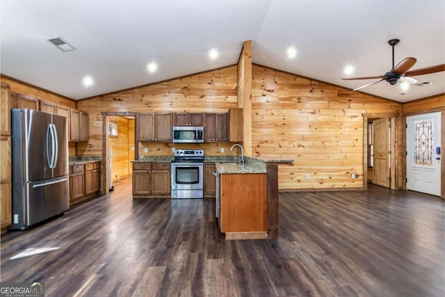 kitchen with lofted ceiling, stainless steel appliances, wooden walls, and dark wood-type flooring