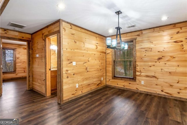 unfurnished dining area featuring wooden walls, dark hardwood / wood-style flooring, and a chandelier