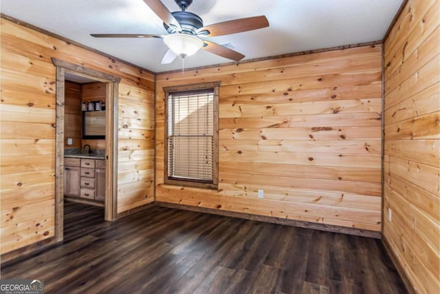 empty room with wooden walls, ceiling fan, dark wood-type flooring, and sink