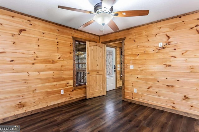 spare room with dark hardwood / wood-style floors, ceiling fan, and wooden walls