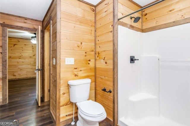 bathroom featuring wood walls, ceiling fan, toilet, walk in shower, and wood-type flooring