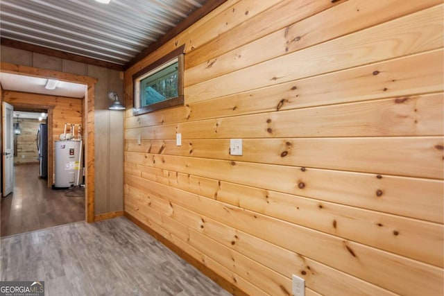 corridor with dark hardwood / wood-style floors, water heater, and wood walls