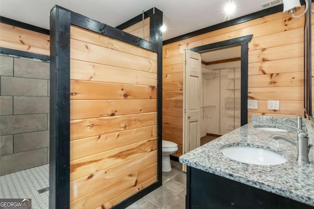 bathroom featuring tile patterned floors, wooden walls, vanity, and toilet