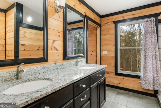 bathroom with wood walls, tile patterned flooring, vanity, and a healthy amount of sunlight