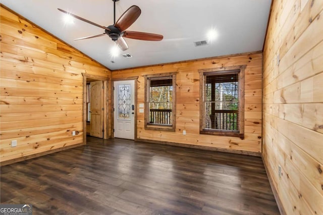 spare room featuring dark hardwood / wood-style floors, vaulted ceiling, ceiling fan, and wood walls