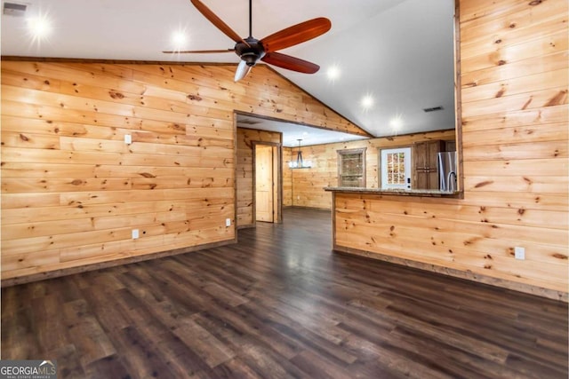 unfurnished living room featuring dark wood-type flooring, high vaulted ceiling, ceiling fan, and wooden walls