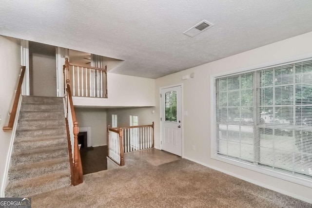 foyer with carpet floors and a textured ceiling