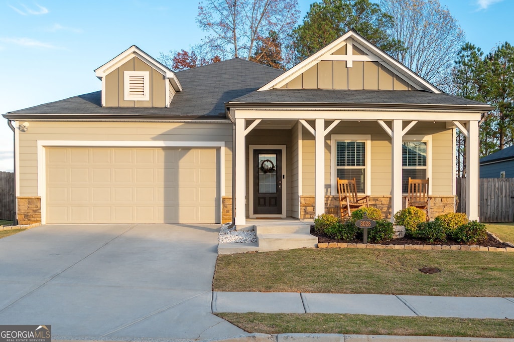 view of front of home featuring covered porch, a front yard, and a garage