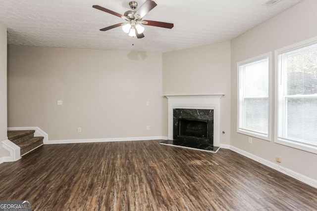 unfurnished living room featuring a textured ceiling, a fireplace, ceiling fan, and dark wood-type flooring