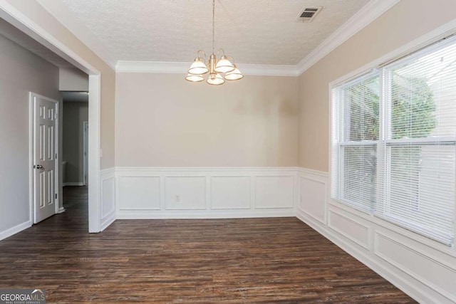 spare room featuring a textured ceiling, dark hardwood / wood-style flooring, crown molding, and a notable chandelier