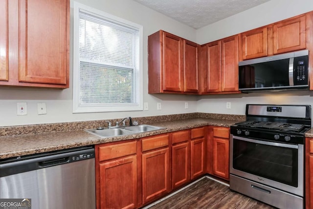 kitchen with a textured ceiling, dark hardwood / wood-style flooring, sink, and appliances with stainless steel finishes