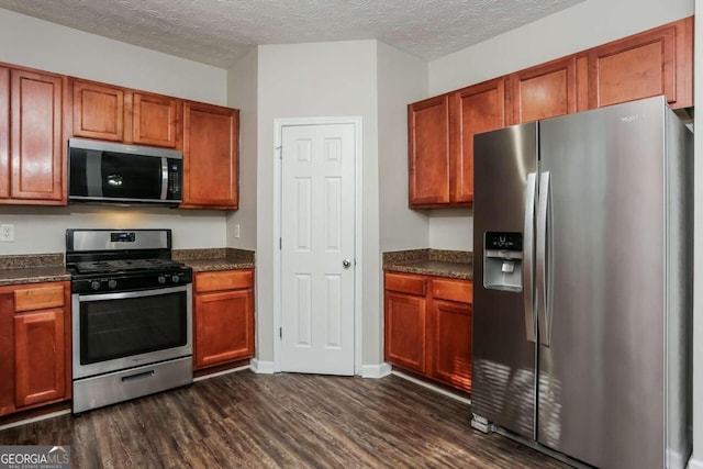 kitchen featuring dark wood-type flooring, stainless steel appliances, and a textured ceiling