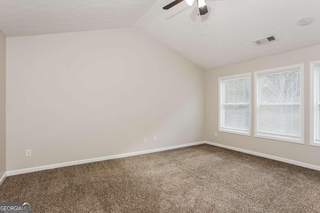 carpeted empty room featuring a textured ceiling, ceiling fan, and vaulted ceiling