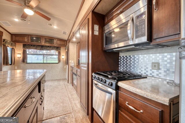 kitchen with tasteful backsplash, ceiling fan, appliances with stainless steel finishes, and light stone countertops