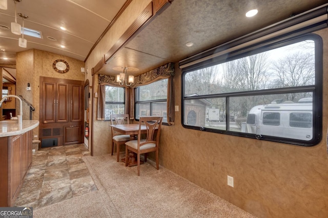 dining room with lofted ceiling, recessed lighting, stone tile flooring, and an inviting chandelier