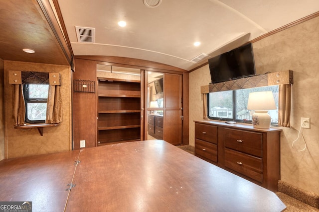 kitchen with built in features, lofted ceiling, brown cabinetry, and visible vents