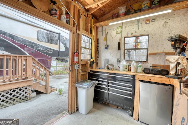 kitchen with concrete flooring, vaulted ceiling, and freestanding refrigerator