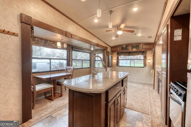 kitchen with lofted ceiling, ceiling fan, range, a kitchen island, and light colored carpet