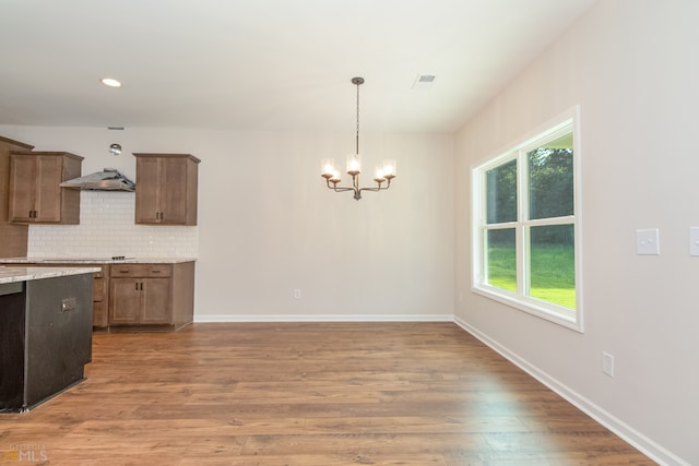 kitchen with decorative backsplash, pendant lighting, a chandelier, and hardwood / wood-style flooring