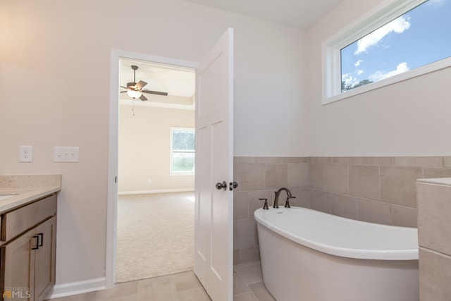 bathroom with vanity, ceiling fan, tile walls, tile patterned flooring, and a tub