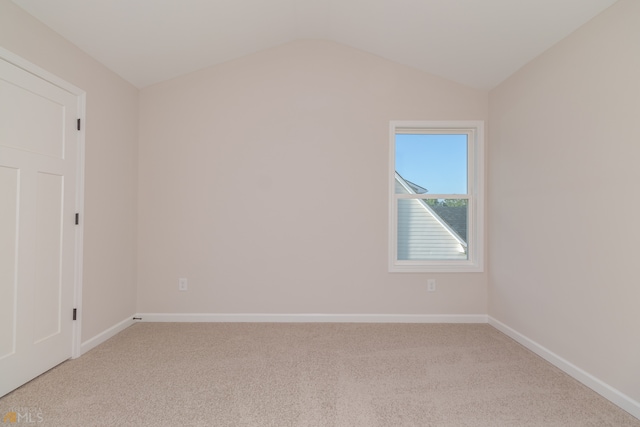 carpeted empty room featuring vaulted ceiling