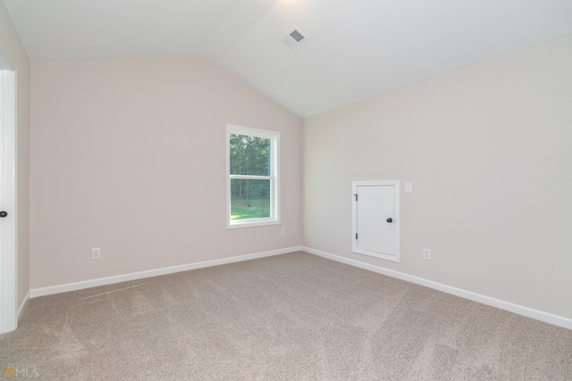 carpeted empty room with lofted ceiling