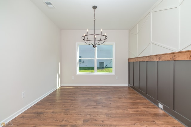 unfurnished dining area featuring dark hardwood / wood-style floors and a notable chandelier