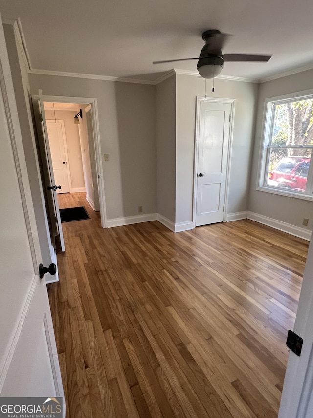 unfurnished bedroom with ceiling fan, ornamental molding, and hardwood / wood-style flooring