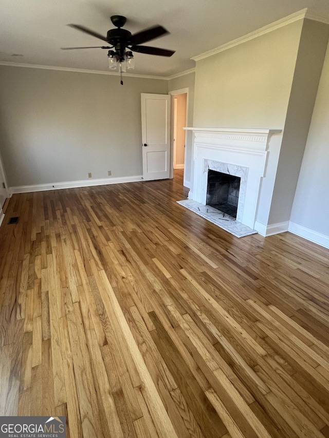 unfurnished living room with ceiling fan, a fireplace, wood-type flooring, and ornamental molding