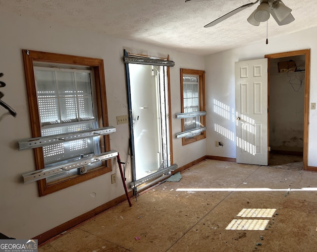 doorway featuring ceiling fan and a textured ceiling