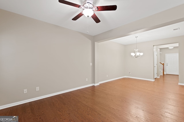 unfurnished room with ceiling fan with notable chandelier and hardwood / wood-style flooring