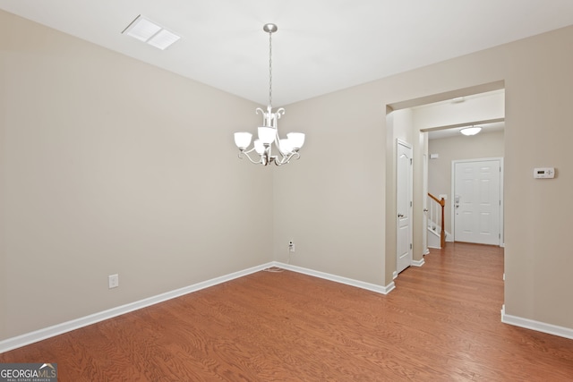 spare room with hardwood / wood-style floors and a chandelier