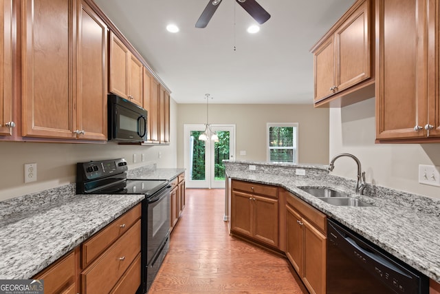 kitchen featuring black appliances, light hardwood / wood-style floors, light stone countertops, and sink