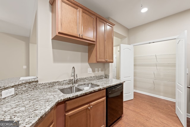 kitchen featuring black dishwasher, light stone counters, light hardwood / wood-style flooring, and sink