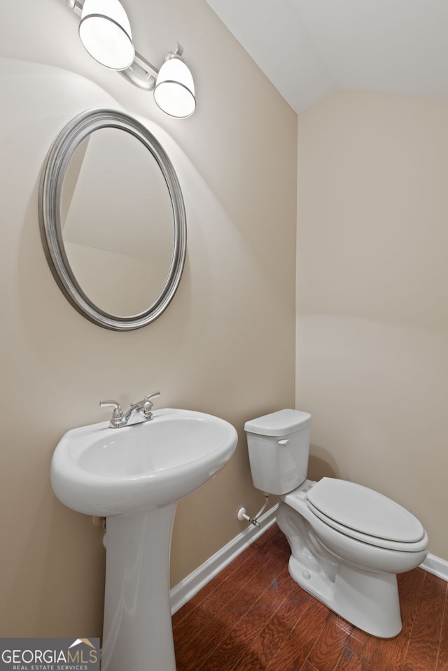 bathroom with toilet, hardwood / wood-style floors, and vaulted ceiling