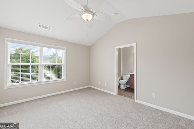 unfurnished bedroom featuring ensuite bath, ceiling fan, light carpet, and lofted ceiling