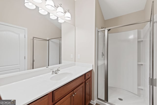 bathroom featuring vanity, a shower with shower door, and vaulted ceiling