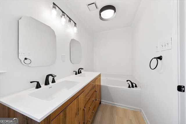 bathroom with hardwood / wood-style flooring, vanity, and a bathing tub