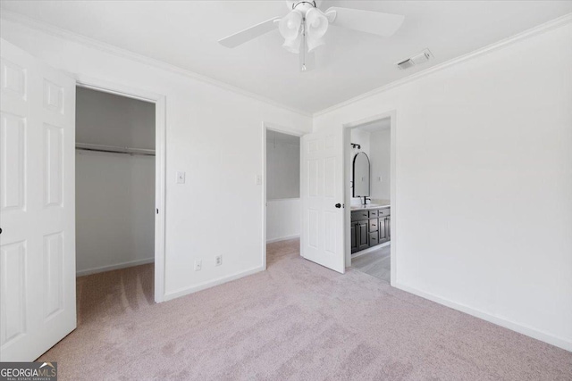 unfurnished bedroom featuring crown molding, light colored carpet, a spacious closet, and a closet