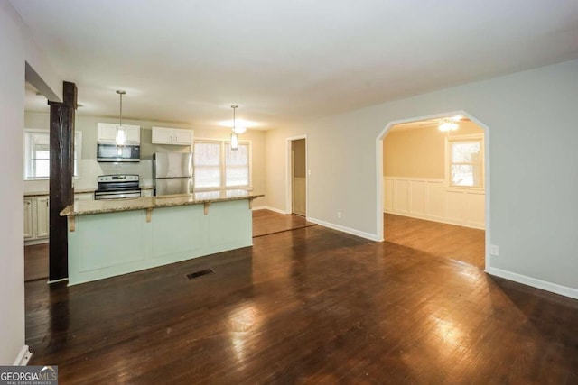 kitchen with white cabinets, a wealth of natural light, stainless steel appliances, and hanging light fixtures